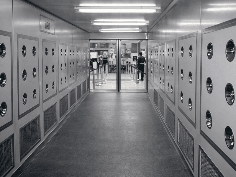 Industrial air shower tunnel with stainless steel walls and multiple high-speed air nozzles for personnel decontamination.